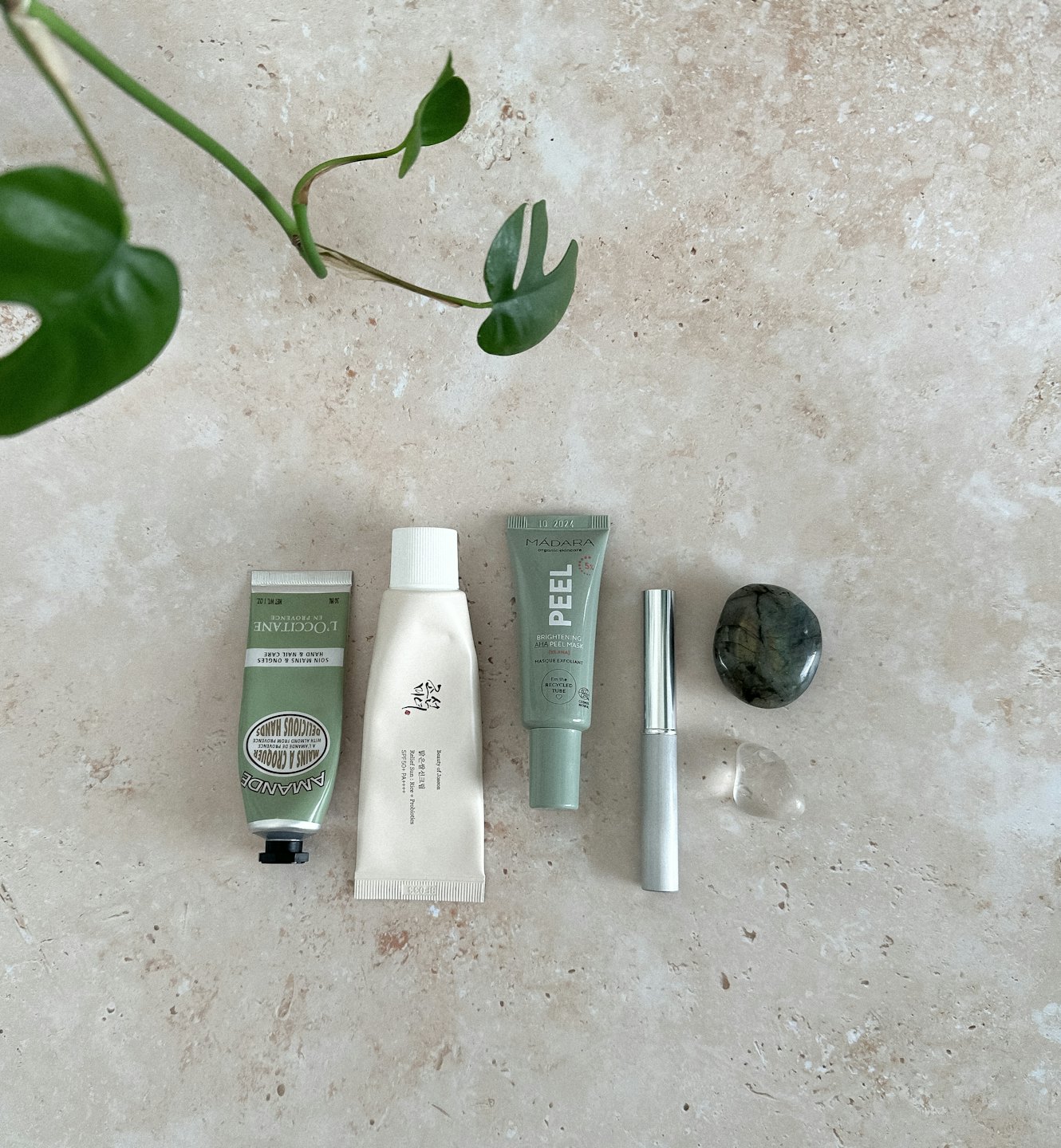Skincare products and beauty tools arranged on a light beige surface.